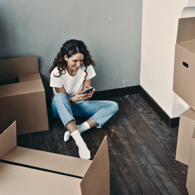 A girl calling a movning company surrounded by boxes